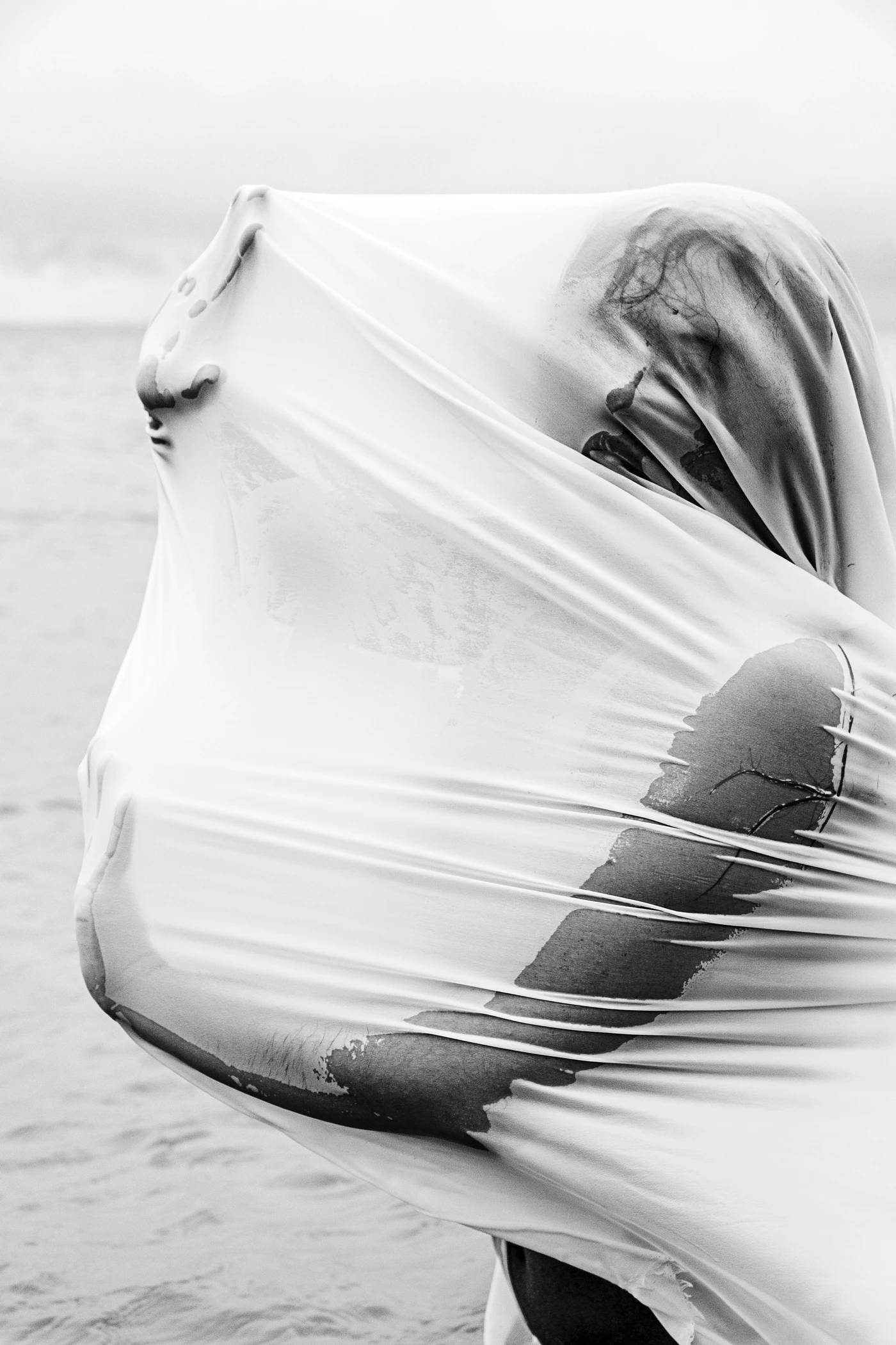 Black and white photograph of young woman wrapped in wet, white chiffon